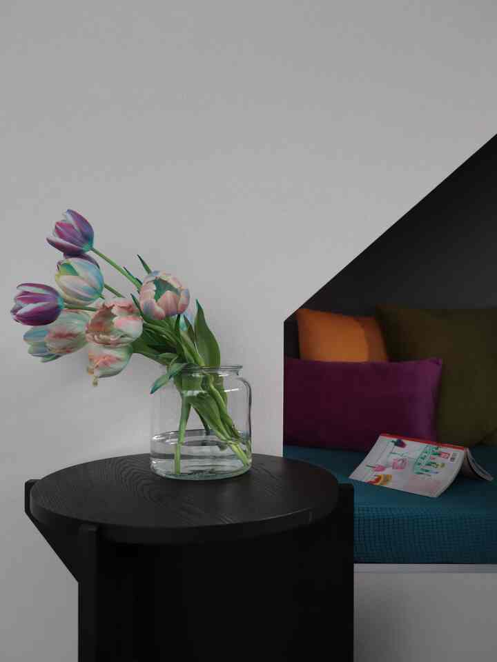 Natural living room with white walls featuring a black side table topped with a transparent vase holding tulips