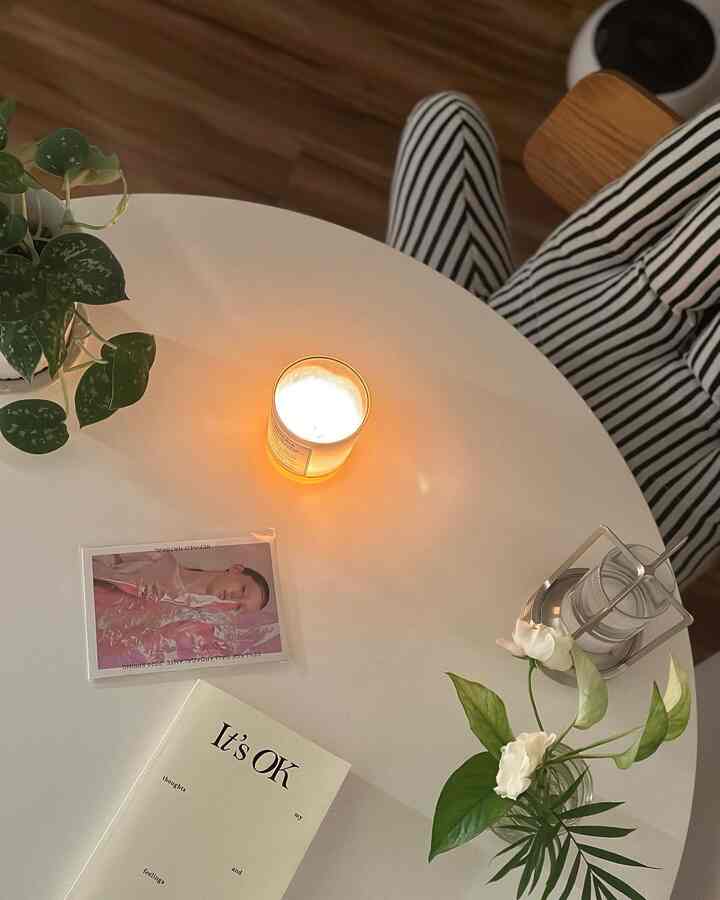 明るいホワイトのダイニングルーム、中央にキャンドルと植物が置かれた丸テーブルが配置されたシンプルで落ち着いたインテリア