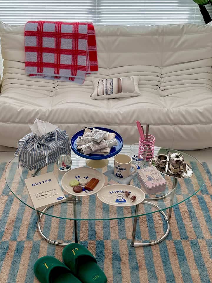 White and blue toned living room featuring a glass coffee table and white sofa with cozy atmosphere