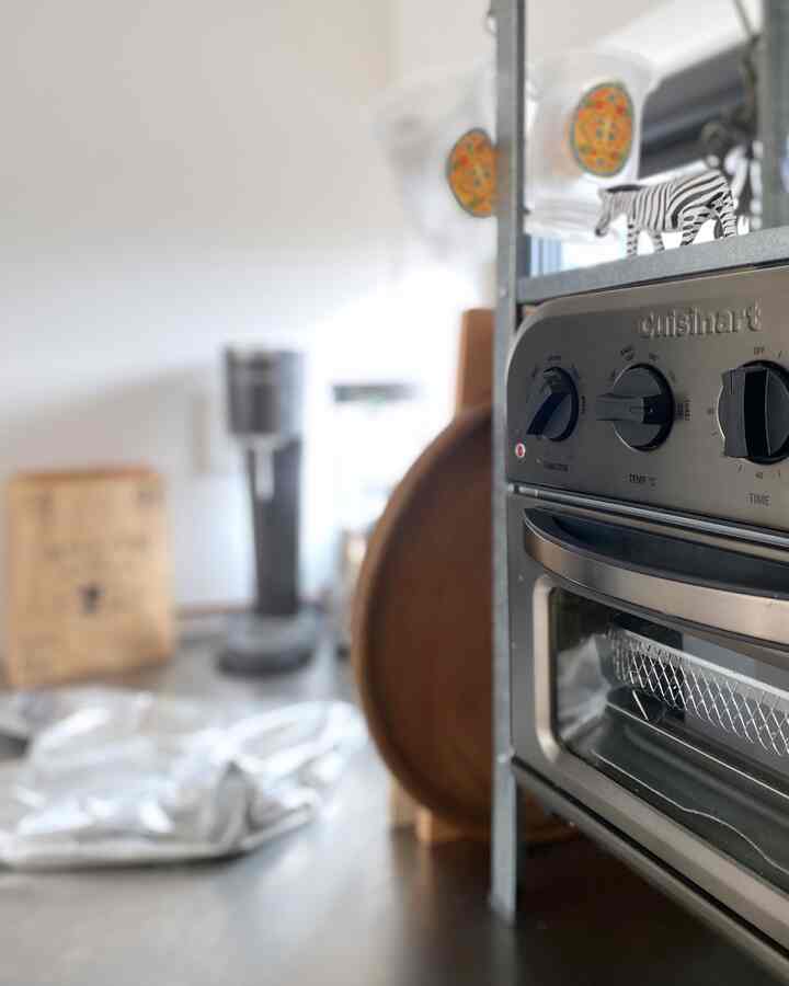 シルバーとホワイトの色調のキッチン、イケアの棚とクイジナートのオーブントースターが配置された印象的な空間