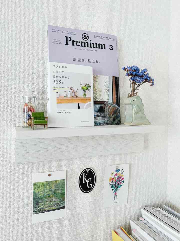 白い壁と壁に取り付けられた家具棚、フレンチカントリースタイルの小物と本が配置された雰囲気のある壁面インテリア