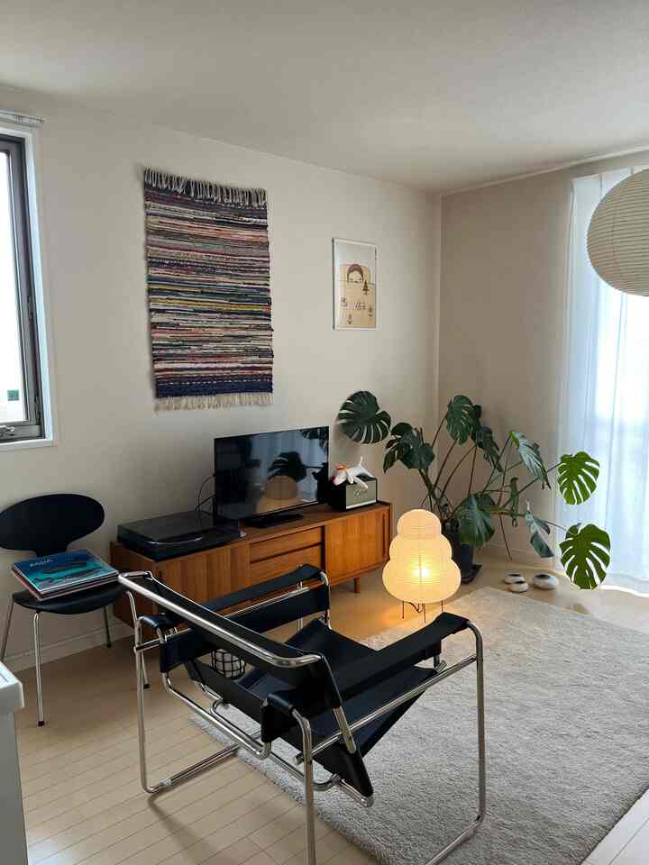 黒と木目調の調和がとれたリビング、ミッドセンチュリーモダンの家具と白いフロアランプが配置された雰囲気のある空間