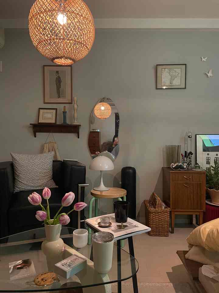 ベージュと木目調のシンプルモダンなリビング、黒い革のアームチェアと花瓶が配された雰囲気のある空間