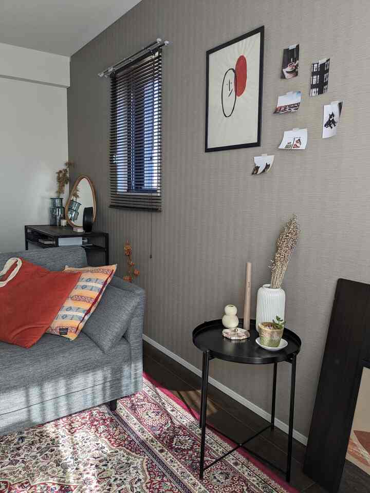 Gray-tone wall and gray sofa with black side table and blinds in a natural-feeling living room space