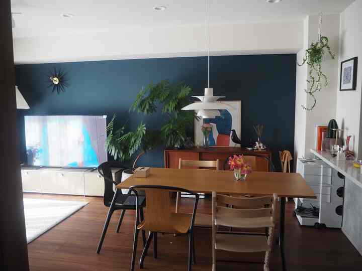 Natural wood tone and navy-walled dining room for a 4-person household featuring pendant light and dining chairs in a cozy modern setting