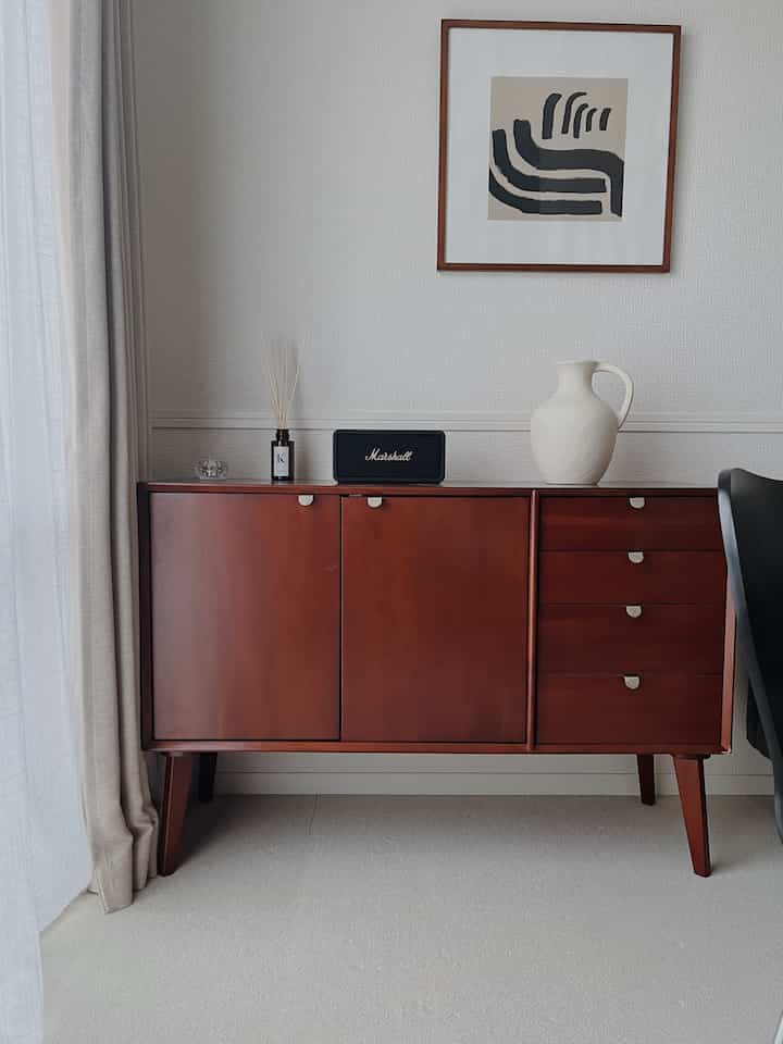 ブラウン色のチェストが配置された、シンプルでナチュラルな雰囲気のリビング