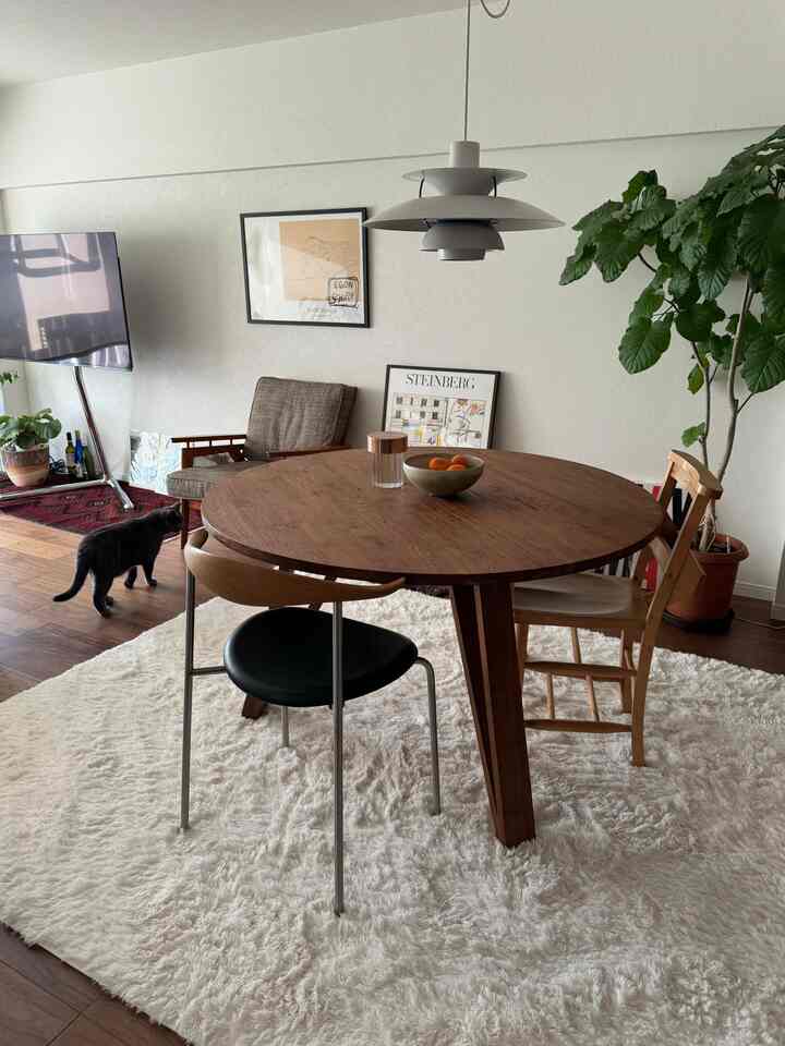 ホワイトと木目調のリビングダイニングルーム、丸いダイニングテーブルと多様な椅子が配置されたモダンで温かみのある空間