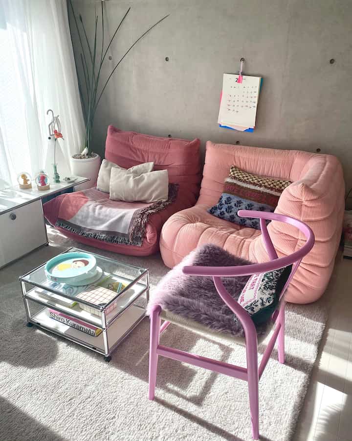 明るく自然な色調のリビング、ピンクのソファとYチェアが配置された雰囲気のある空間