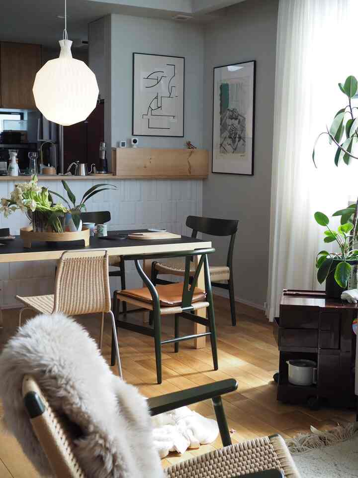 明るいホワイトと木目調が調和する北欧風のリビング、アームチェアとダイニングチェアが配置された居心地の良い空間