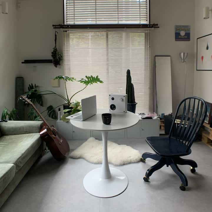 白を基調とした北欧風の一人暮らし向けホームオフィス、緑の植物が配置された落ち着いた空間