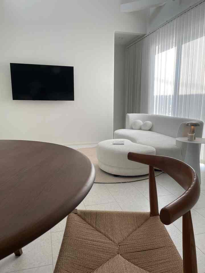 Modern living room in white and brown tones featuring a round dining table and sofa with a clean, harmonious atmosphere