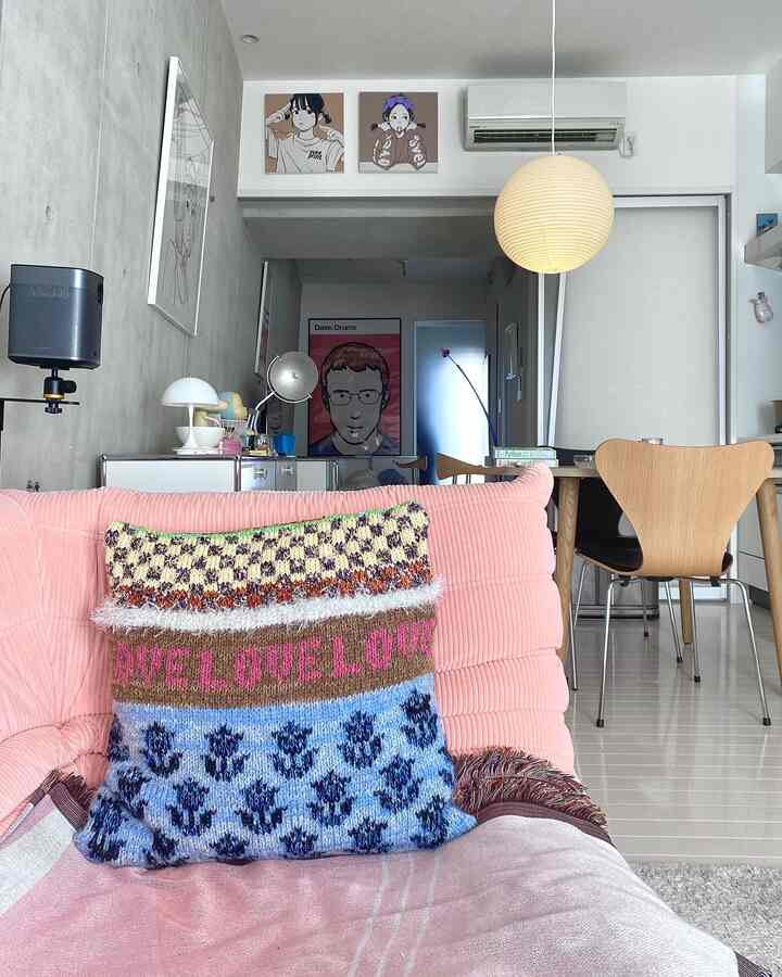 Modern living and dining space featuring a pink corduroy sofa with colorful cushions and wall art