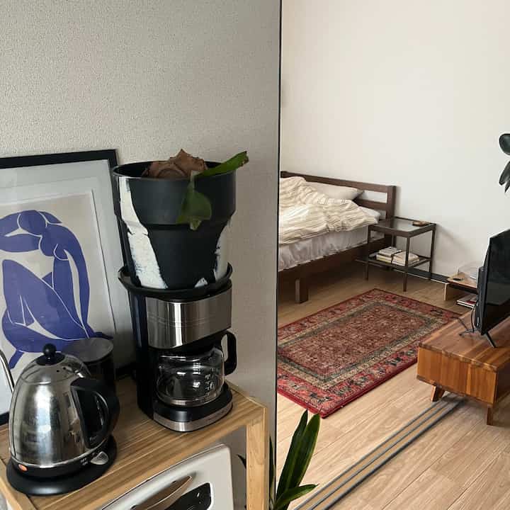 ナチュラルカラーのワンルームで、寝室とおうちカフェが調和した雰囲気あるインテリア