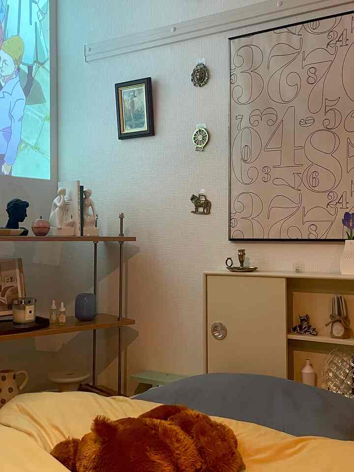 ナチュラルなベージュと木目調の寝室のコーナー、居心地の良いベッドと個性的なウォールアートが配置された雰囲気のあるインテリア