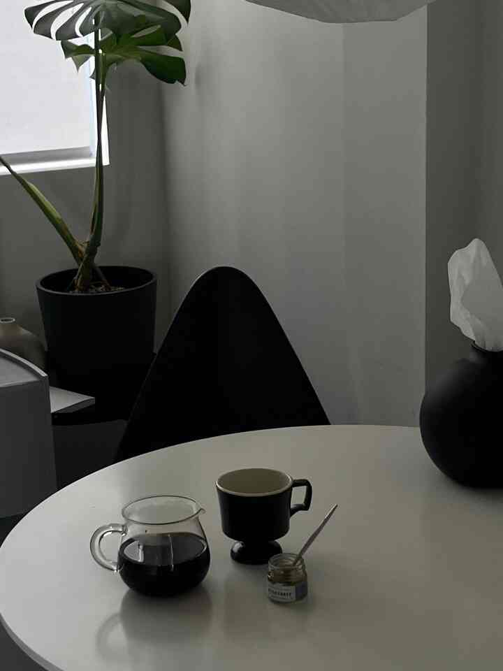 白いテーブルと黒い椅子が配置されたカフェ風のおうちカフェ空間、植物とコーヒー器具で雰囲気のあるインテリア