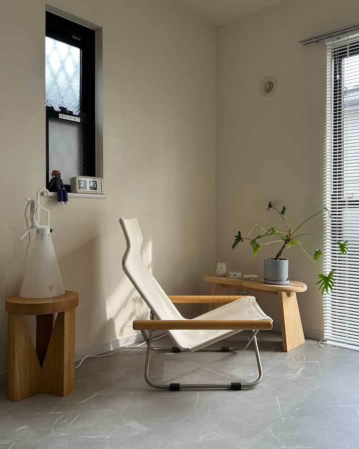 Natural color and white-toned living room featuring a natural modern armchair, bench, and plant in a simple and minimal space