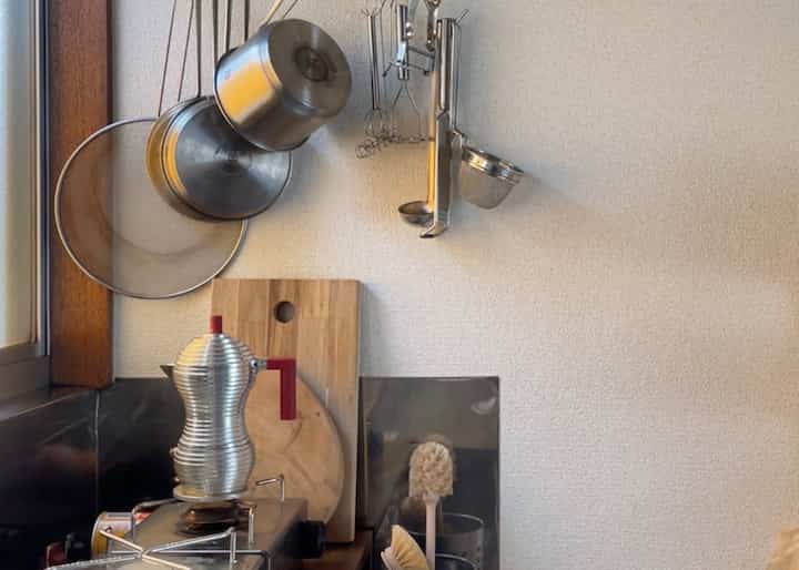 A kitchen space with silver and wood tones features an espresso coffee maker and neatly arranged kitchen utensils, evoking a calm morning atmosphere