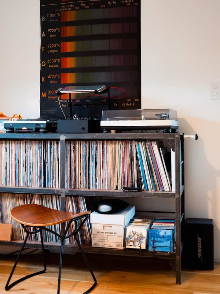 Natural brown toned living room shelf featuring record player and numerous vinyl records in a minimal music space