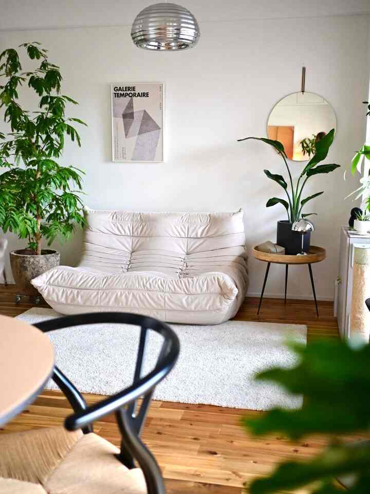 白と緑のトーンのリビングルーム、自然素材の家具と植物が調和したミニマルで雰囲気のあるインテリア