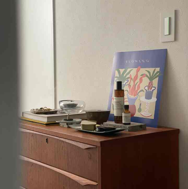 Cozy entrance with soft beige walls and wood tone cabinet, featuring art poster and diffuser objects arranged on top