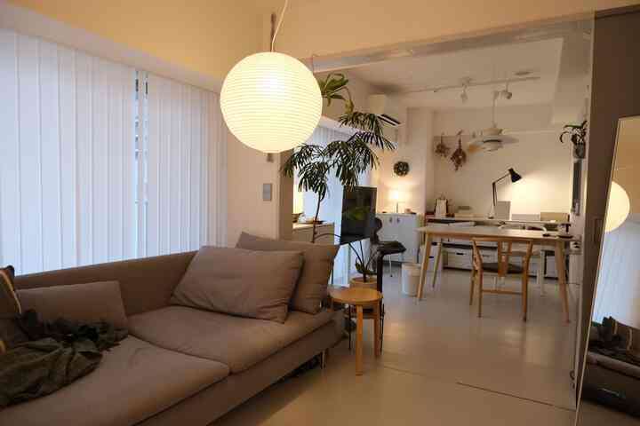 Beige and white toned living room and home office space featuring sofa and dining chairs in a clean natural modern style interior