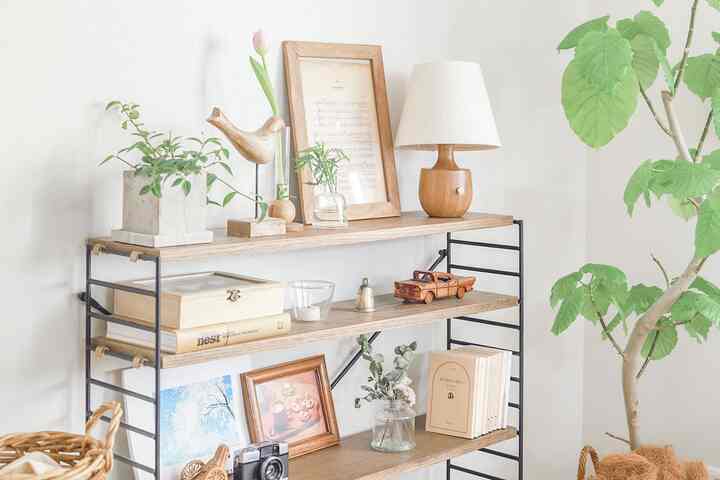 ナチュラルな色調の壁に設置された木製の棚と植物、テーブルランプが配置された雰囲気のあるインテリア
