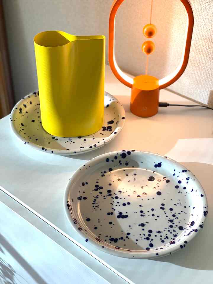 Cozy space featuring a white dining table with a yellow pitcher and speckled plates