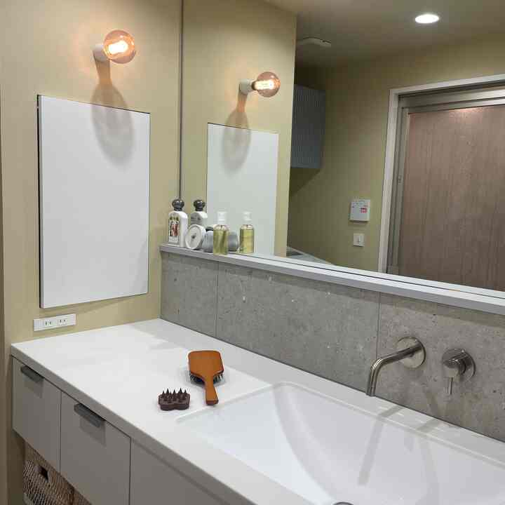Modern bathroom space with beige walls and white sink area, featuring wall sconces and large mirror
