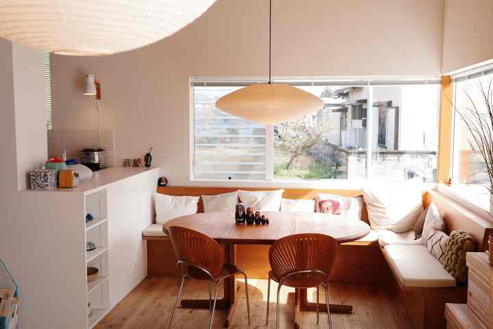 ナチュラルカラーと木目調が調和したダイニング、窓辺に造作ベンチとペンダントライトが配置された雰囲気のある空間