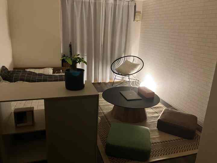 白と茶色のトーンのワンルーム寝室、小さな丸テーブルとアームチェアが配置された雰囲気のある空間