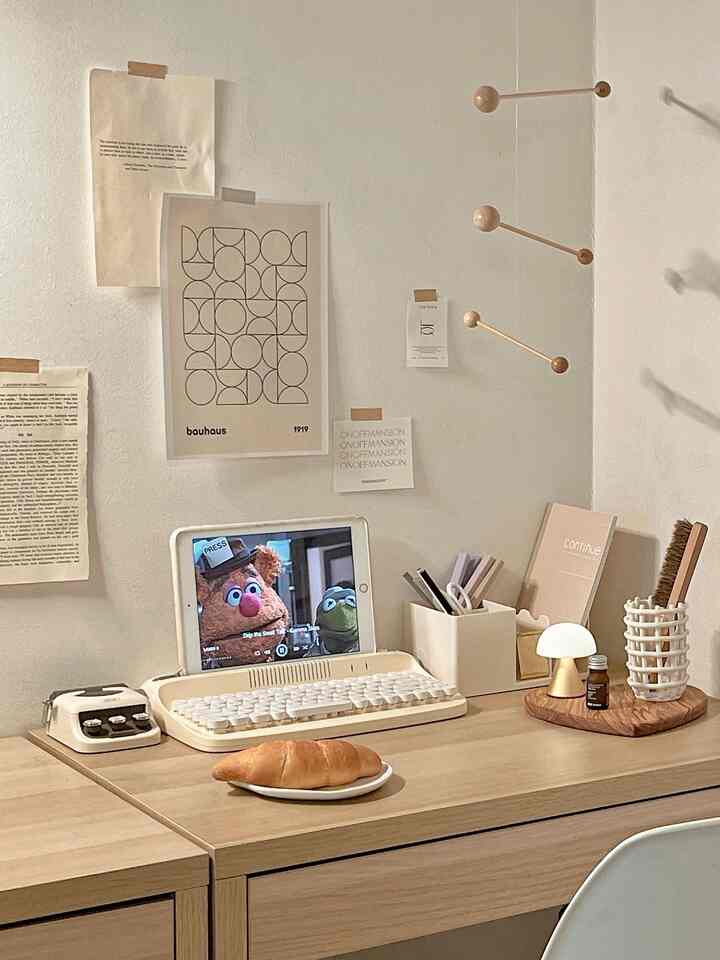 白い壁と木目調のデスクが配置されたシンプルモダンなホームオフィス、デスクオーガナイザーとテーブルランプが設置されている