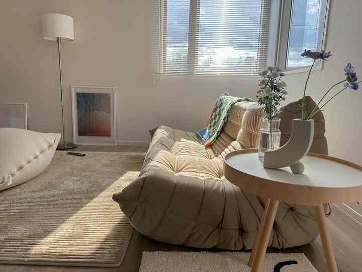 ナチュラルなベージュ色調のリビング、ビーズクッションソファとウッドのサイドテーブル、柔らかな自然光が差し込む居心地の良い空間