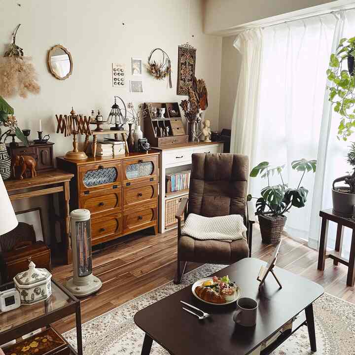 ブラウン調のリビング、木製家具とアームチェアが配置され、白いカーテンと植物が自然な雰囲気を醸し出すインテリア