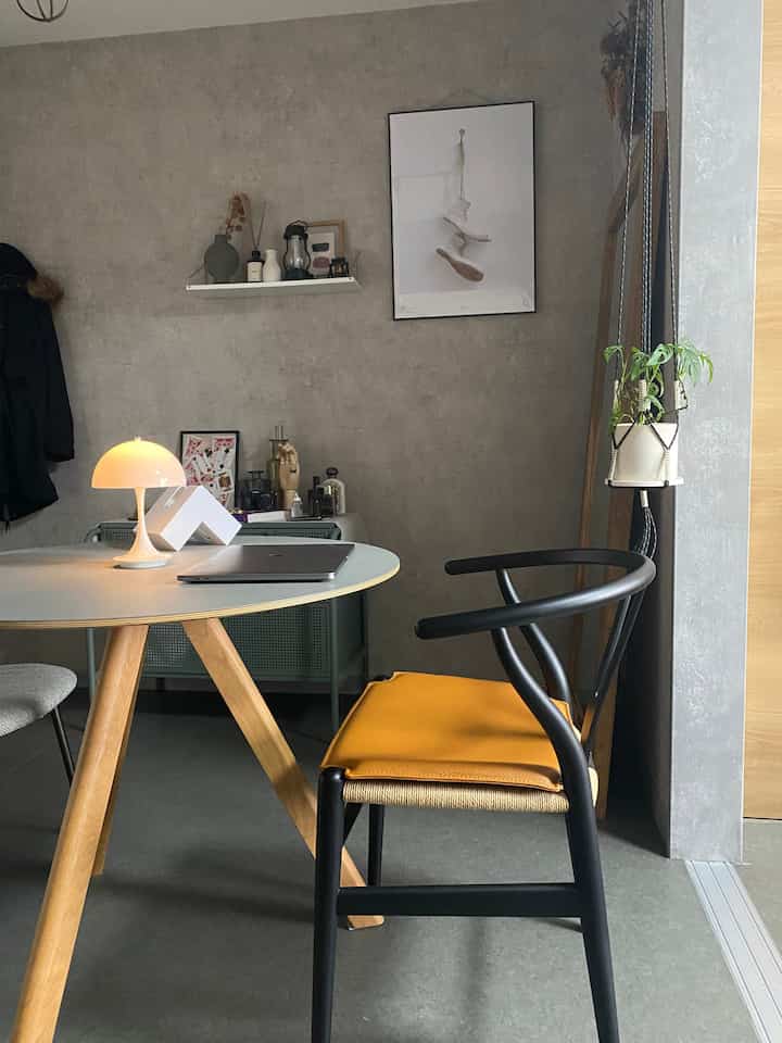 ナチュラルトーンのラウンドテーブルと黒いYチェアが配置された、シンプルで落ち着いた雰囲気のモダンなダイニングルーム