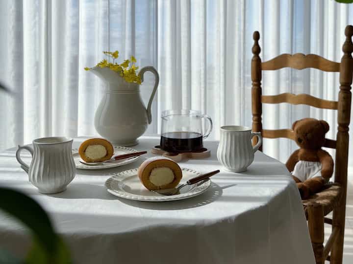 ホワイトとナチュラルな色調のカフェ風ダイニング、コーヒーとおやつが並ぶ落ち着いた雰囲気のインテリア