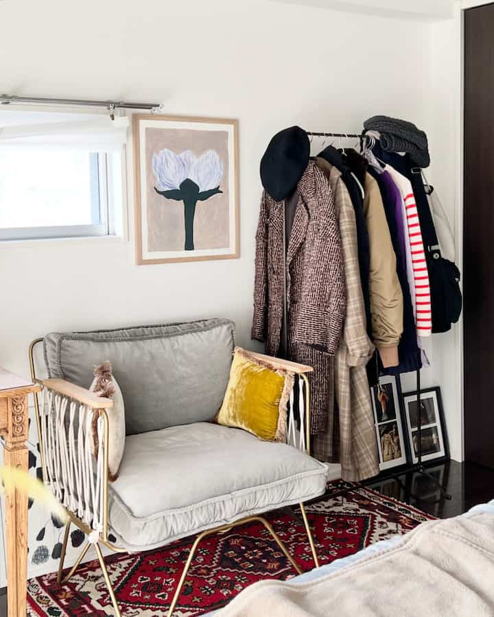 Beige and gray toned bedroom featuring an armchair centered with a red patterned rug creating a cozy atmosphere