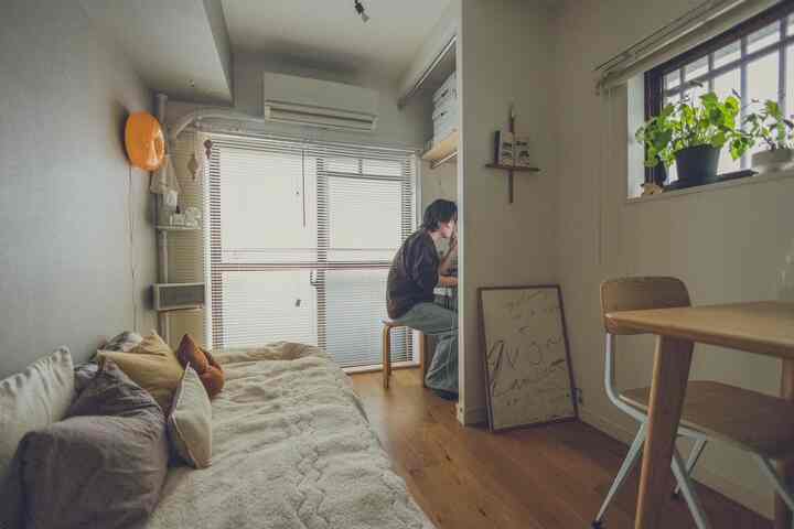 Bright white and warm wood-toned small studio with natural wooden desk and beige sofa, creating a simple modern home office space