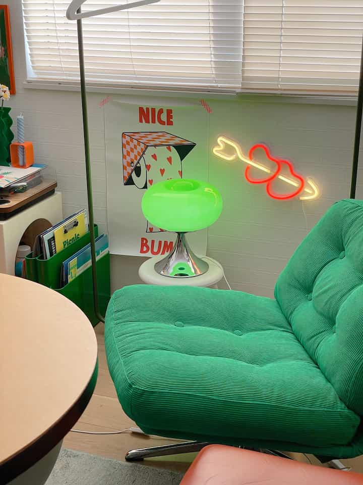 Green-toned living room featuring an armchair and table lamp creating a cozy retro style space