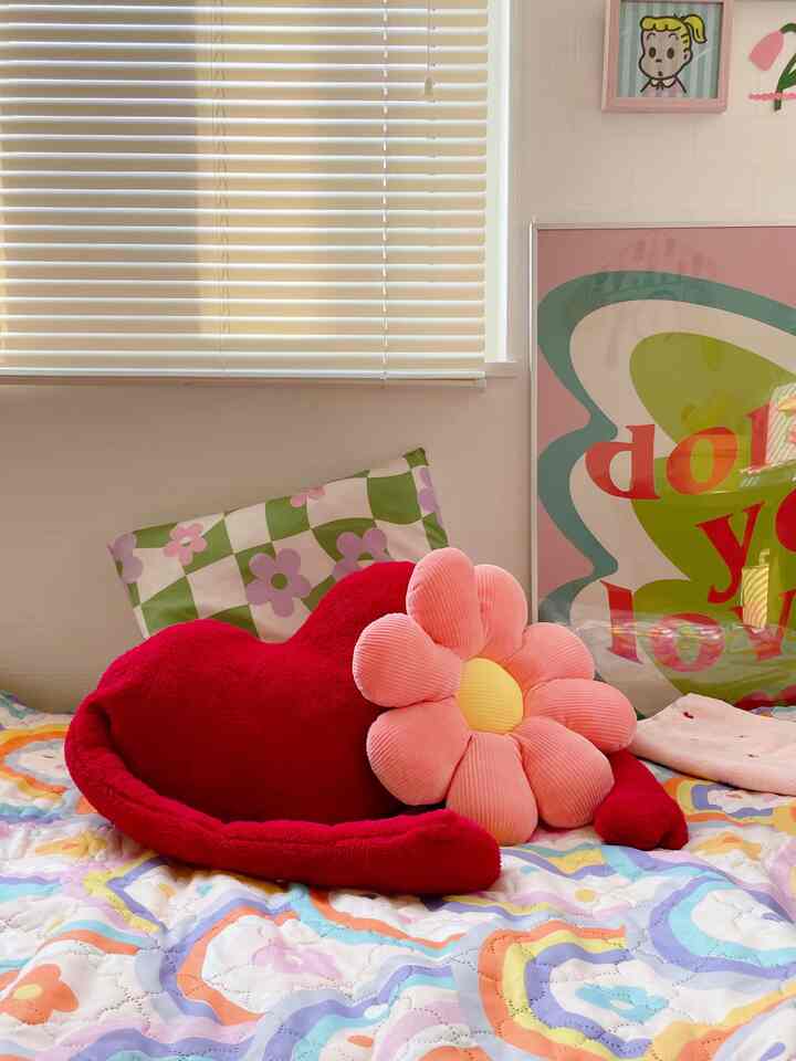 カラフルな柄の寝具に、ハート型と花型のクッションが置かれた雰囲気のある寝室