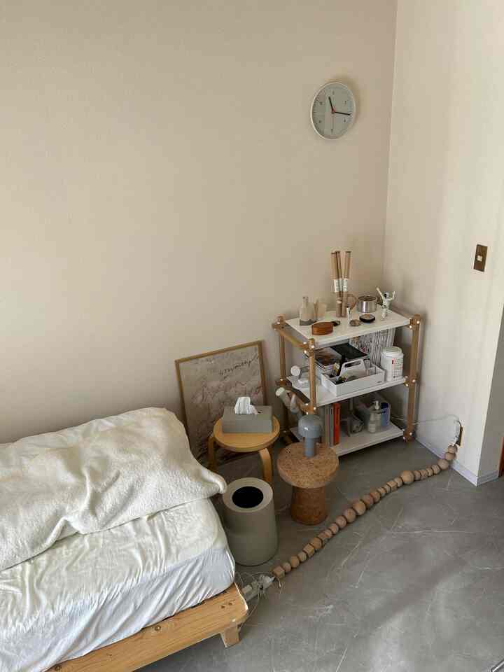 A narrow bedroom with white and wood tones, featuring side tables and shelving in a clean natural modern style interior