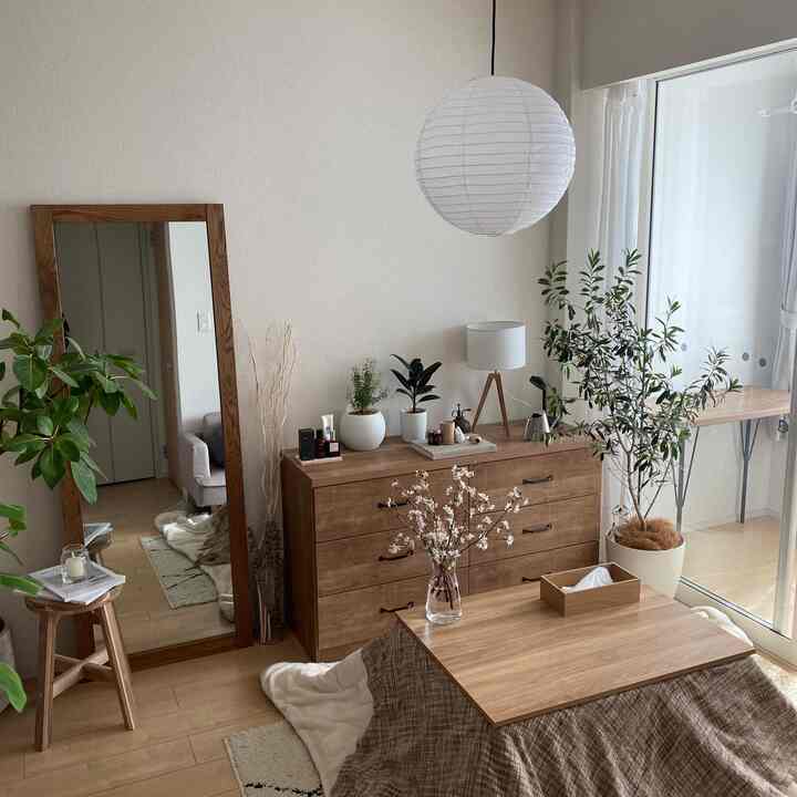 A wood-tone and white living room featuring a kotatsu table and plants, creating a warm natural atmosphere