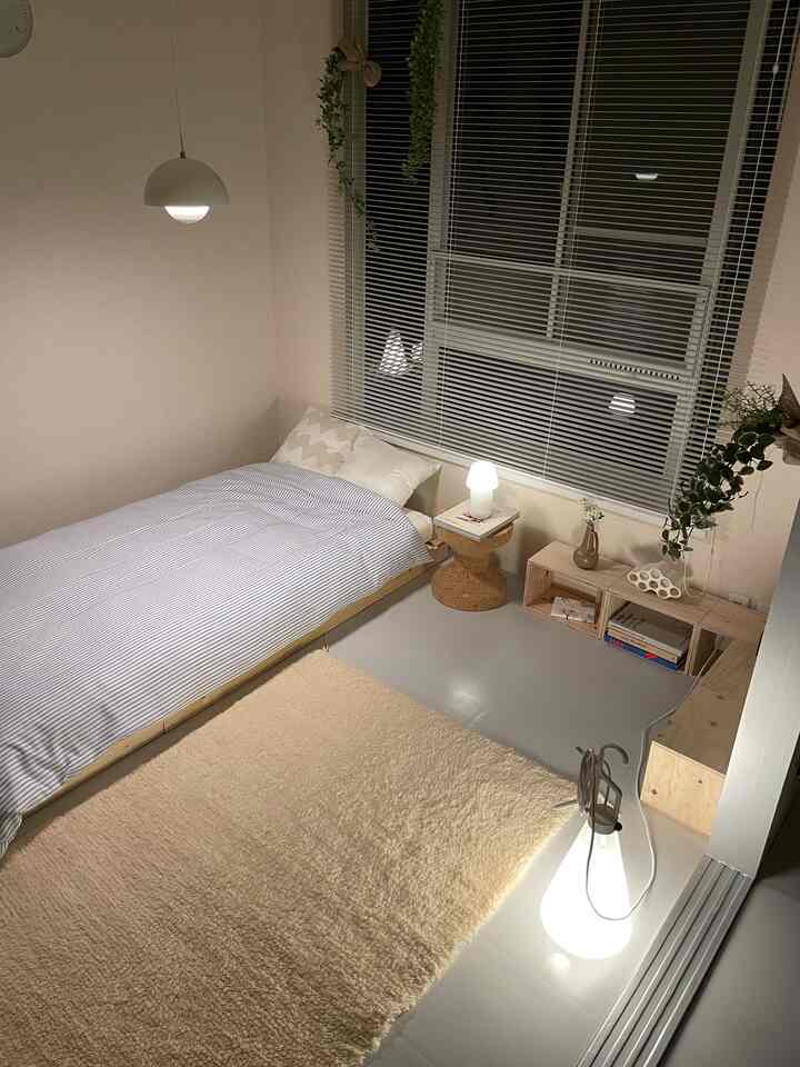 白と木目調の調和したコンパクトな寝室、ベッドとキューブボックスの収納棚が配置された自然で落ち着いた印象的な空間