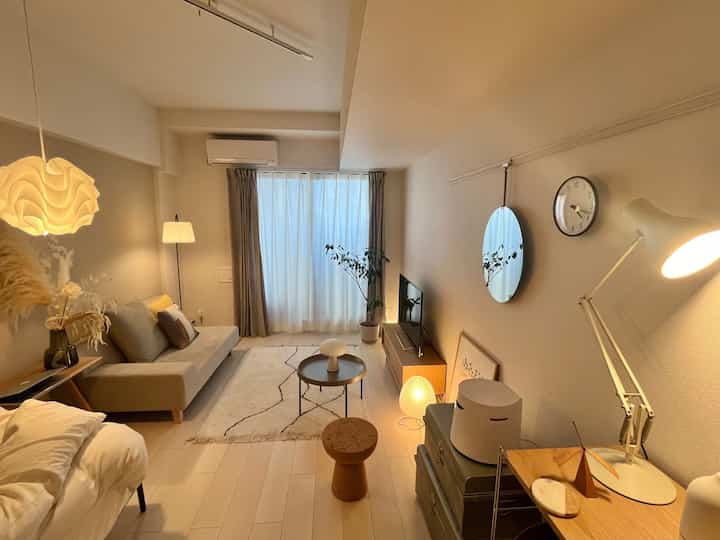 ベージュとホワイトの色調のリビング、モダンでナチュラルモダンなソファと多様な照明が配置された雰囲気のある空間