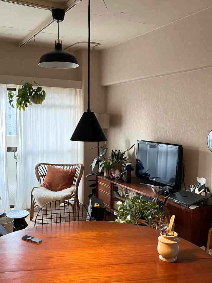 ナチュラルな木目調のリビング・ダイニングルーム、ラタンチェアとテレビ台が配置された落ち着いた雰囲気の空間