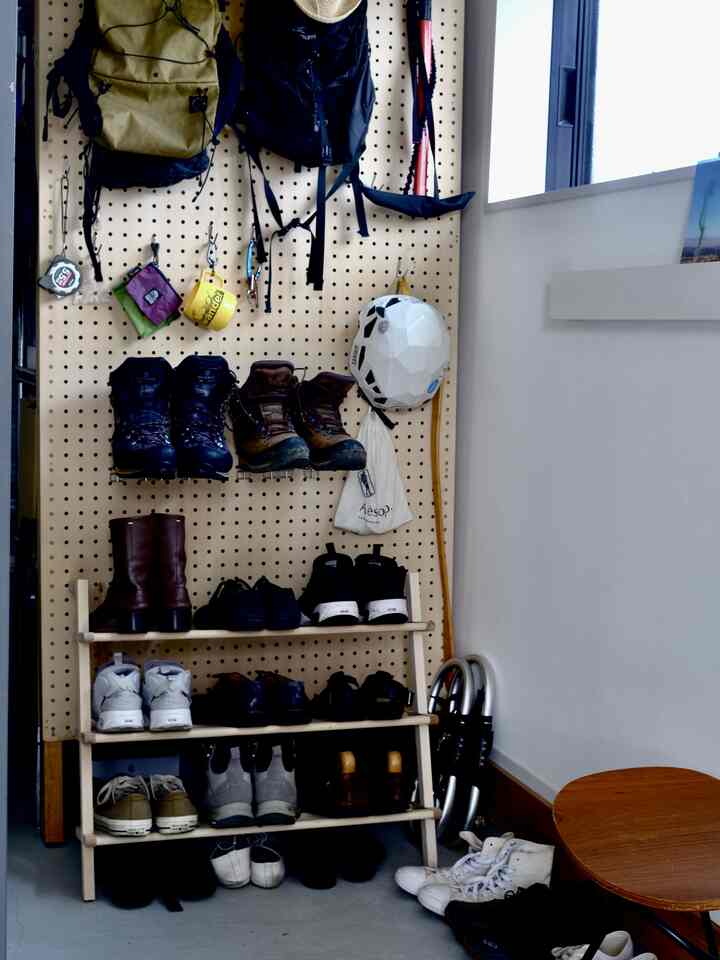 ナチュラルカラーの玄関、実用的な収納スペースにシューズラックとアイゼンやヘルメットが掛けられている