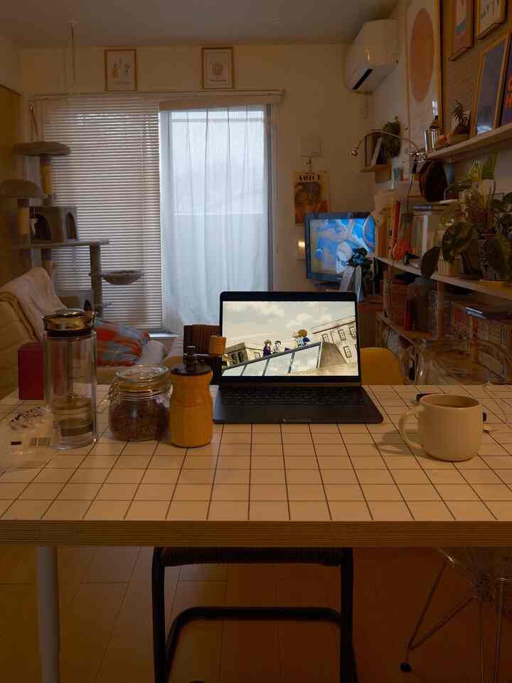 温かみのあるブラウンとホワイトのリビング、中央にノートパソコンとコーヒー用品があるコンパクトなデスクが配置された印象的な空間