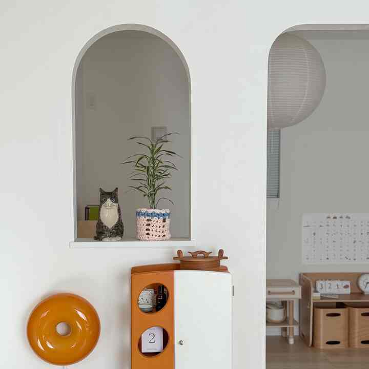 白い壁とアーチ型のくぼみに猫の陶器と植物が置かれたナチュラルなキッチンスペース