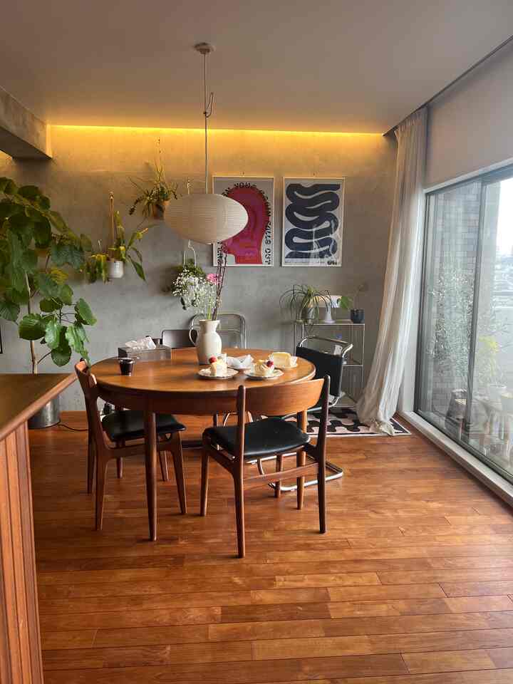 暖かい木目調とグレーの壁が調和したダイニングルーム、丸いダイニングテーブルとペンダントライトが配置されたナチュラルな雰囲気のインテリア