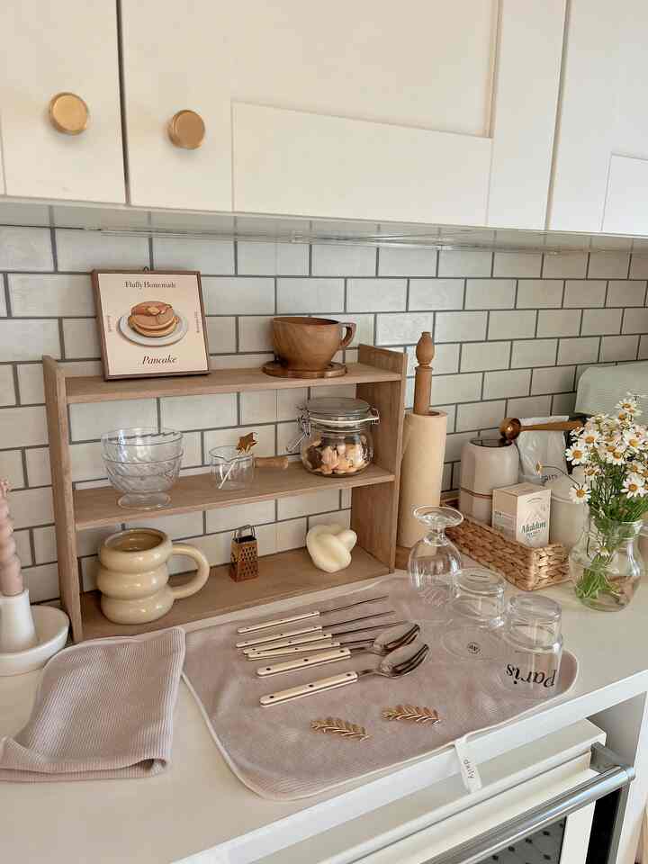 ベージュとウッドトーンのキッチン、キッチンタオルとコースターが整然と置かれた雰囲気のあるインテリア