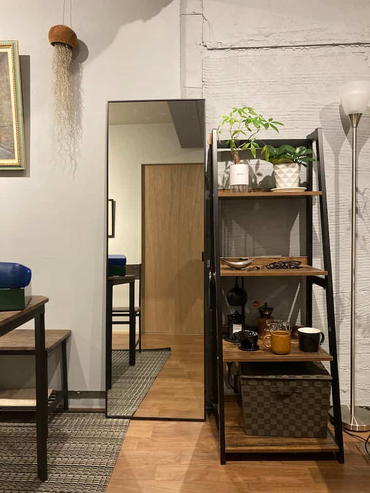 Wood tone floor and black-framed mirror with open shelving arranged in a neat dining room setting